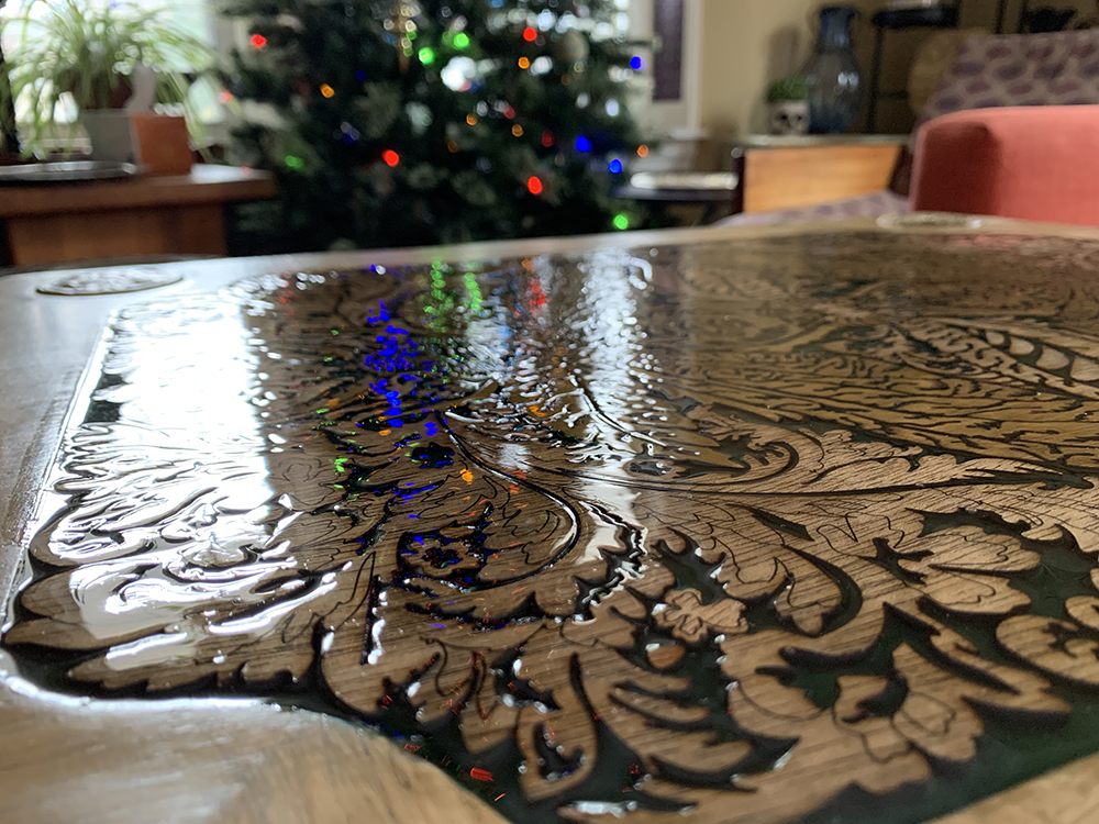 A photo of the table top taken from a close angle, showing how glossy the resin is as it reflects the light of the Christmas tree.
